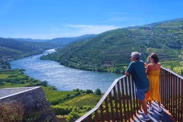 Couple enjoying the panoramic view of the Douro River and vineyard-covered hills from a scenic lookout point.