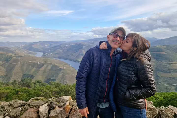 Couple enjoying a scenic view of Douro Valley's lush vineyards during a luxury private wine tour.