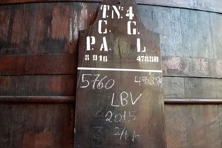 Aged wooden wine barrel with chalk markings in a traditional Douro Valley winery, showcasing authentic wine production.