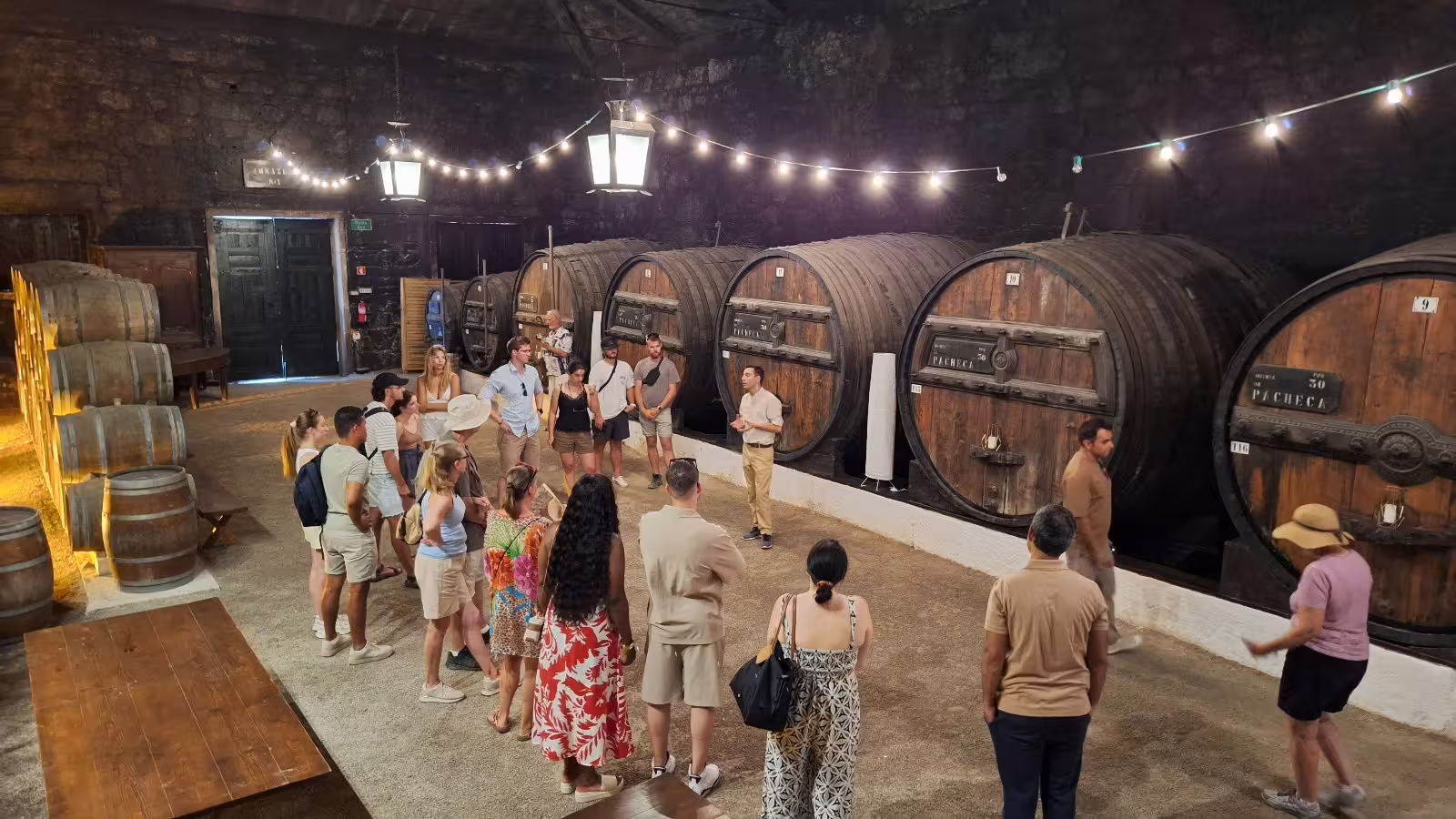 Visitors explore a historic wine cellar with large oak barrels during a private tour in the picturesque Douro Valley wineries.