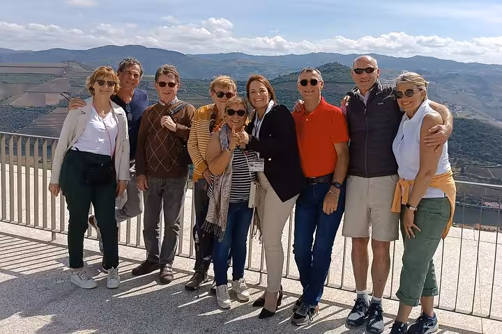 Happy tour group enjoying panoramic Douro Valley vineyard views on a guided wine and boat cruise tour