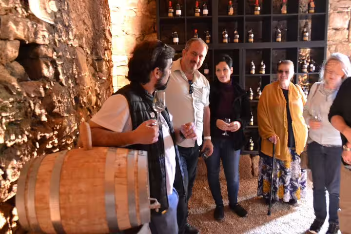 Group enjoying wine tasting in rustic Douro Valley cellar on vineyard tour.