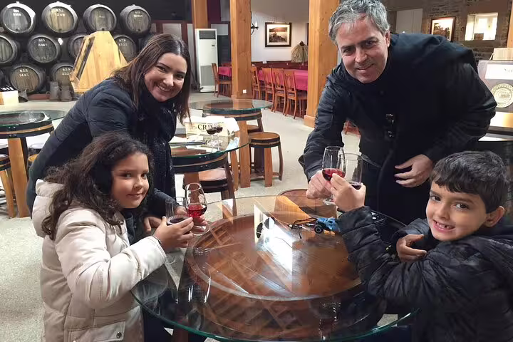 Family enjoying wine tasting at Douro Valley winery with oak barrels in the background.