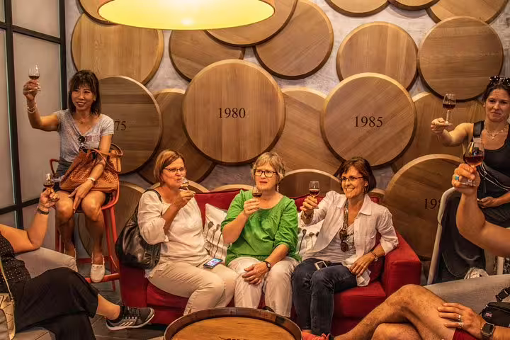 Group enjoying wine tasting in a cozy Douro Valley winery with vintage barrels in the background.