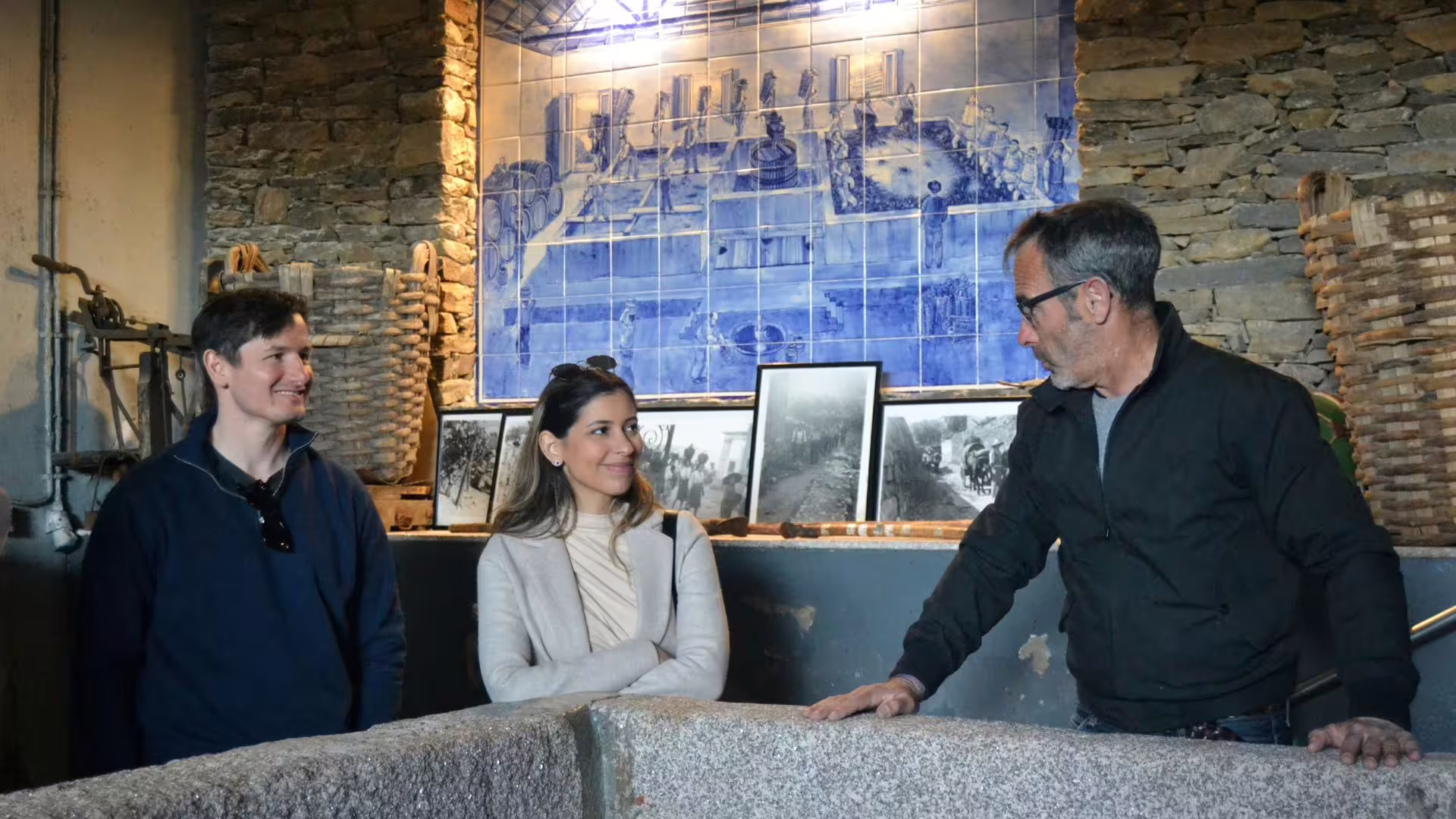 Tour guide discussing wine history with visitors at a Douro Valley winery with traditional decor.