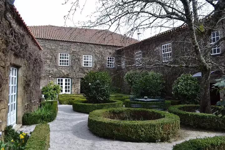 Charming courtyard of a historic Douro Valley winery with manicured hedges and rustic stone architecture.
