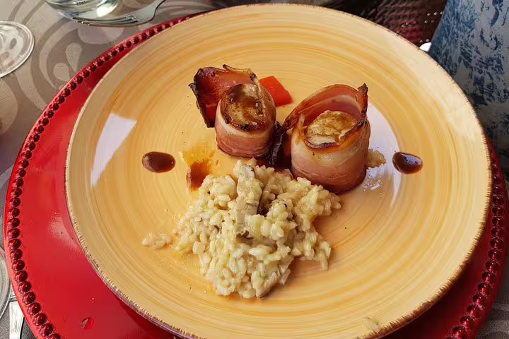 Gourmet meal featuring rolled bacon-wrapped dish with creamy risotto served at a Douro Valley winery.