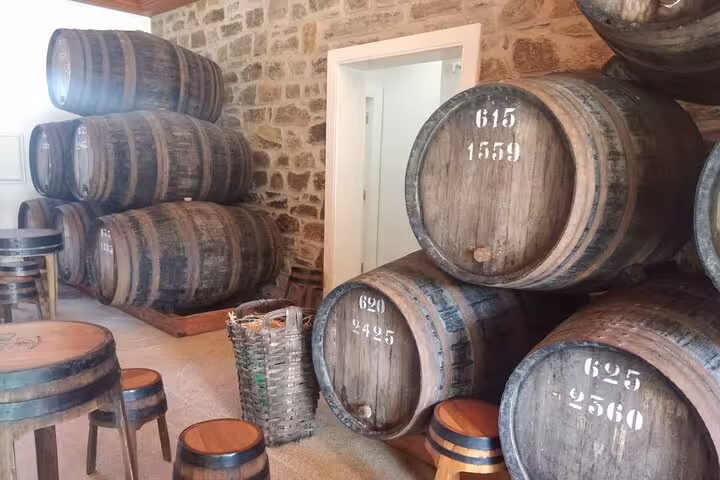 Numbered oak wine barrels stacked in a rustic stone cellar during a Douro Valley winery guided tour