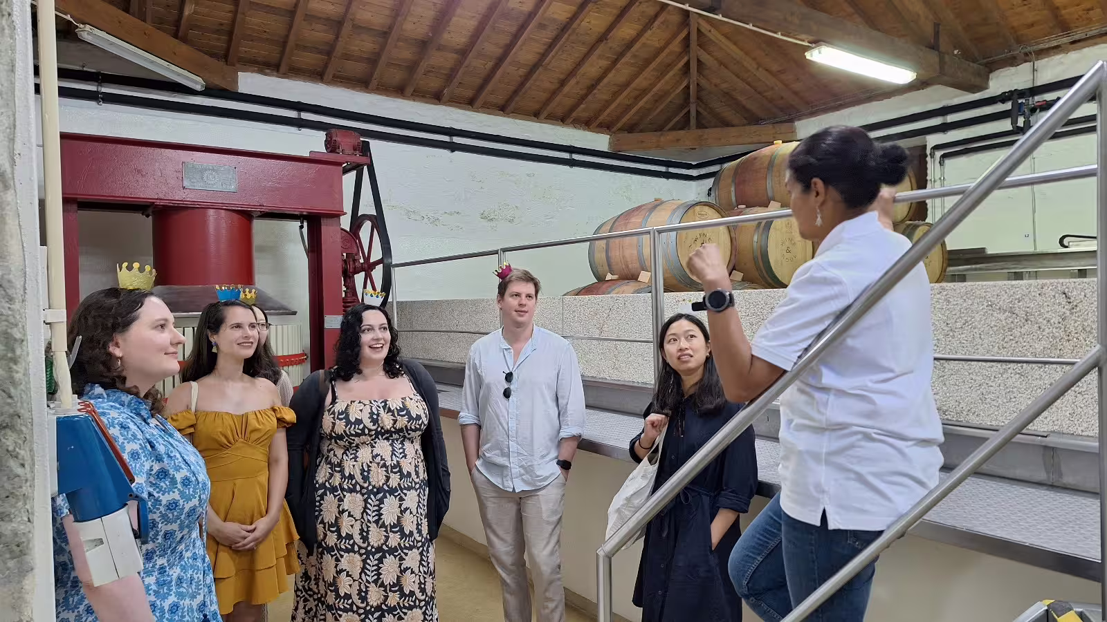 Visitors enjoy a guided tour of a renowned Douro Valley winery, exploring wine barrels and traditional winemaking processes.