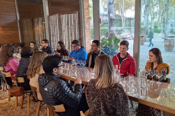Visitors enjoy a wine tasting session at a renowned Douro Valley winery, surrounded by scenic views through large windows.