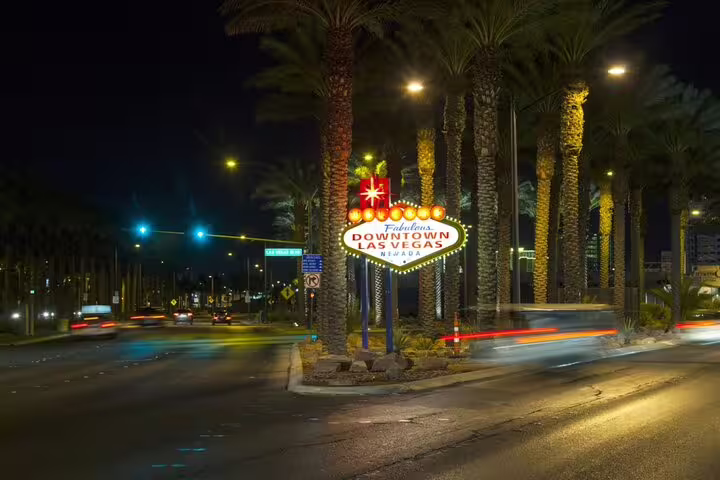 Welcome to Fabulous Downtown Las Vegas neon sign at night with palm trees and light trails