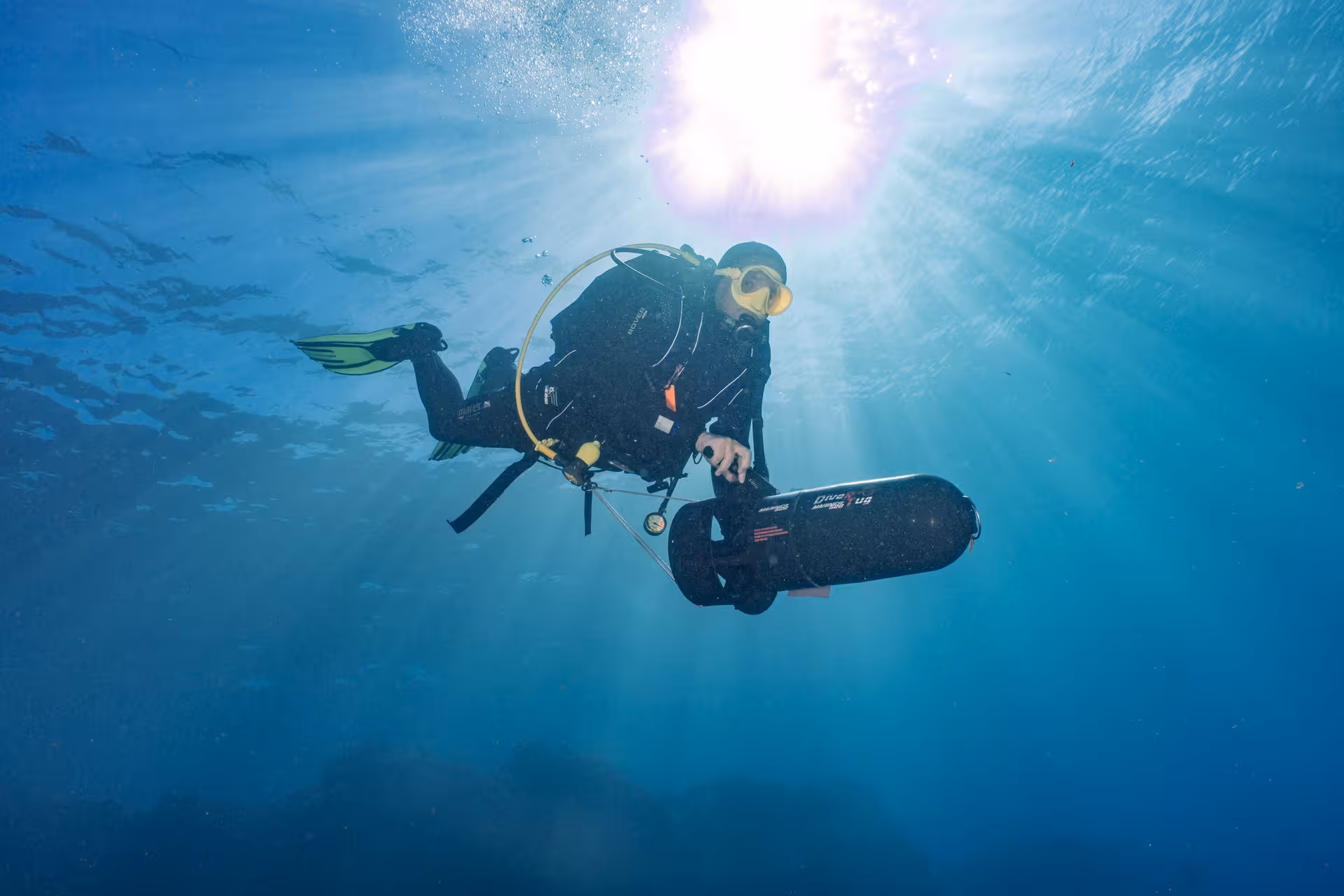 Scuba diver with DPV scooter glides through sunlit waters, highlighting DPV-Scooter Dive Adventure excitement.