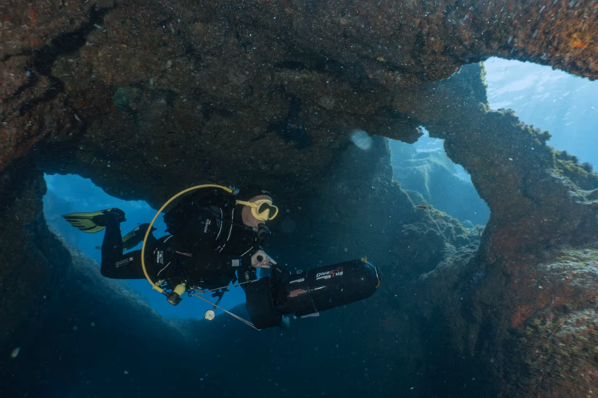 Diver navigates through an underwater cave with a DPV scooter, showcasing thrilling dive exploration.