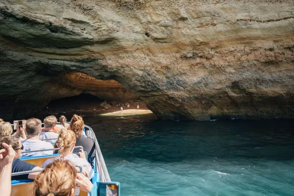 Tourists on a boat explore stunning sea caves during the Dreamer Caves & Dolphin Watching tour, a top Algarve attraction.