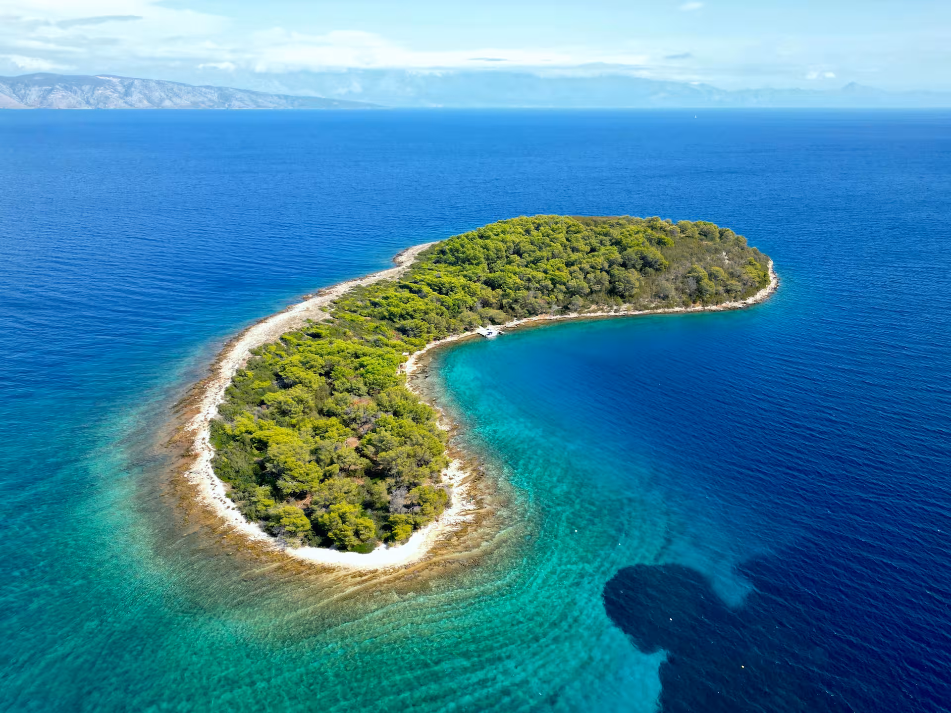Drone view of lush islet and bright Blue Lagoon waters on 3 Islands speedboat tour with swim stop