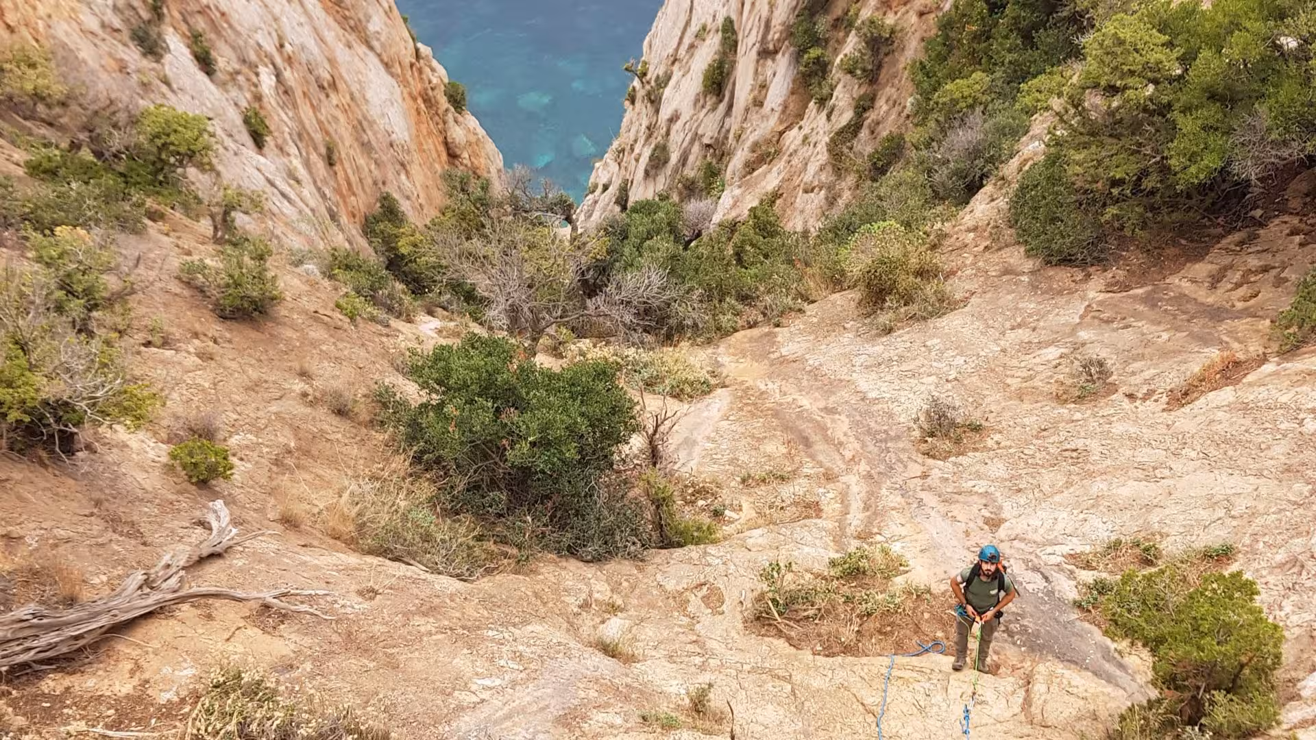 Adventurer navigates rugged terrain during dry canyoning in Porto Flavia, revealing stunning coastal views.