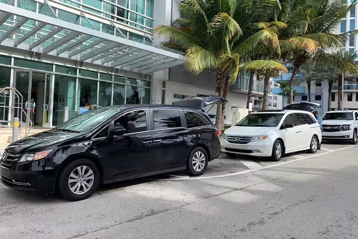Multiple private transfer minivans lined up at hotel entrance for seamless Dubai Airport round-trip transportation service