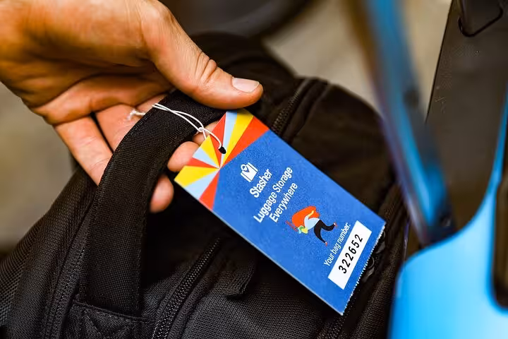 Hand holding a tagged suitcase at Dubai Al Rigga luggage storage, secure bag drop service near metro station