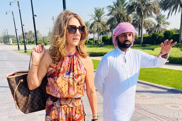 Dubai city tour guide with traveler in palm-lined park, exploring historical and modern highlights in half day