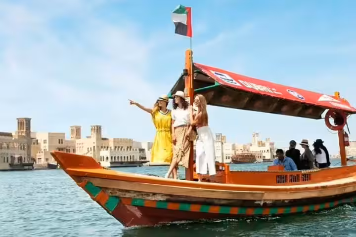 Traditional abra boat tour on Dubai Creek with tourists exploring historic architecture and cultural landmarks.