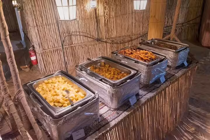 Buffet of hot Arabic dishes and grilled meats set up in a rustic camp for Dubai desert safari BBQ dinner experience