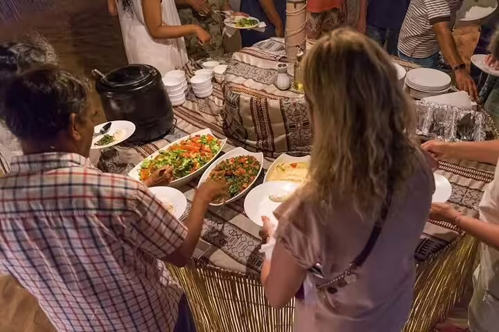 Guests serving themselves traditional salads and Arabic dishes at a buffet during Dubai desert safari BBQ dinner
