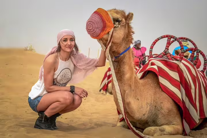 A visitor enjoys a close encounter with a camel during a Dubai desert safari, highlighting the adventure of the tour.
