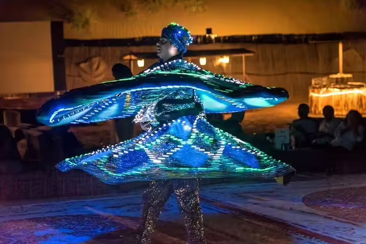 Colorful LED tanoura dancer spinning during live Arabian entertainment on Dubai desert safari evening tour