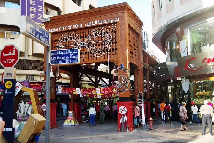 Bustling entrance of Dubai's Gold Souk with shoppers exploring vibrant market on a city sightseeing tour.