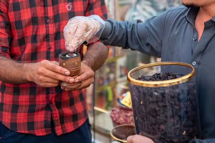 Guide serving authentic Emirati sweets from a jar to a guest on a Dubai walking tour with local street food tastings