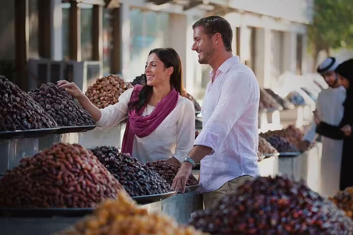 Tourists enjoying a local market in Dubai, selecting fresh dates and experiencing authentic Middle Eastern flavors.