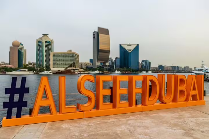 Scenic view of Al Seef Dubai sign with modern skyscrapers and the creek, a highlight of the Dubai Magical Day & Night Tour.