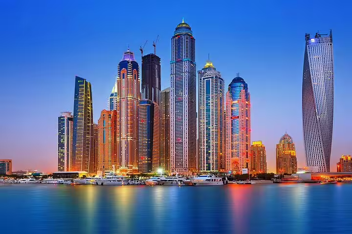 Panoramic skyline of Dubai Marina with illuminated skyscrapers and yachts, featured in a 4x4 city sightseeing tour.