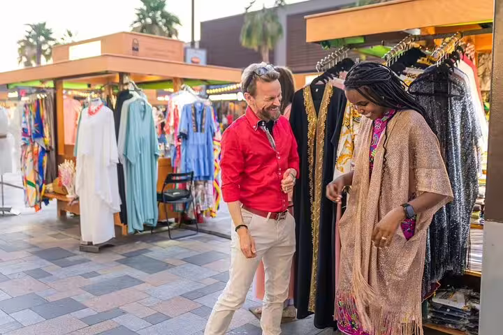 Tour guests browse colorful abaya stalls during a Dubai Marina walking tour, shopping for local fashion and cultural souvenirs