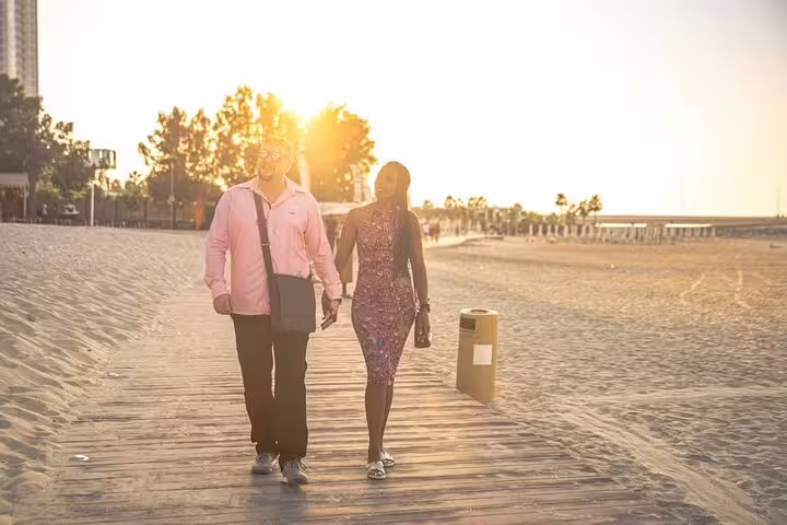 Couple strolling a sunny Dubai Marina beach boardwalk during an evening walking tour with local food tasting experiences