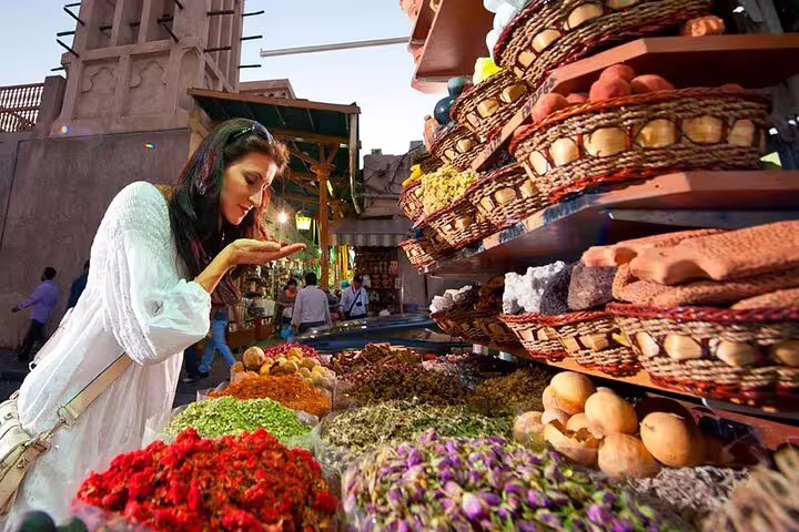 Traveler enjoying aromatic spices at a traditional market in Old Dubai during a full-day private tour.