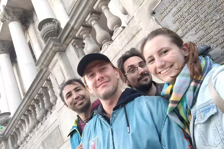 Four friends smiling together outside a historic stone building during a Dublin walking tour