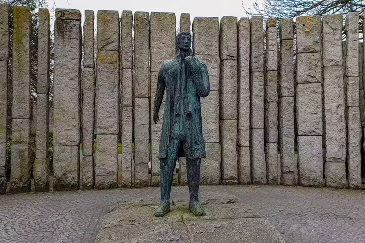 Bronze statue of a figure against tall stone pillars in Dublin, atmospheric ghost tour location