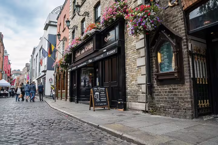 Cobblestone street with traditional Irish pub The Quays in Dublin's Temple Bar area with flower baskets