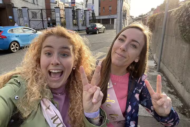Two women smiling and making peace signs on a Dublin street during a guided walking tour