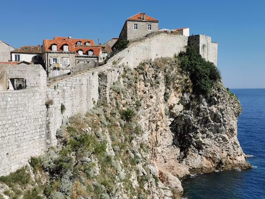 Dubrovnik ancient city walls above seaside cliffs with red-roof houses, highlight of private Old Town combo tour