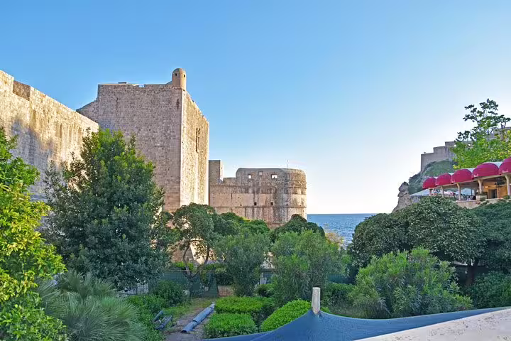 Dubrovnik city walls and fort at sunrise above lush gardens, scenic stop on an early bird walking tour