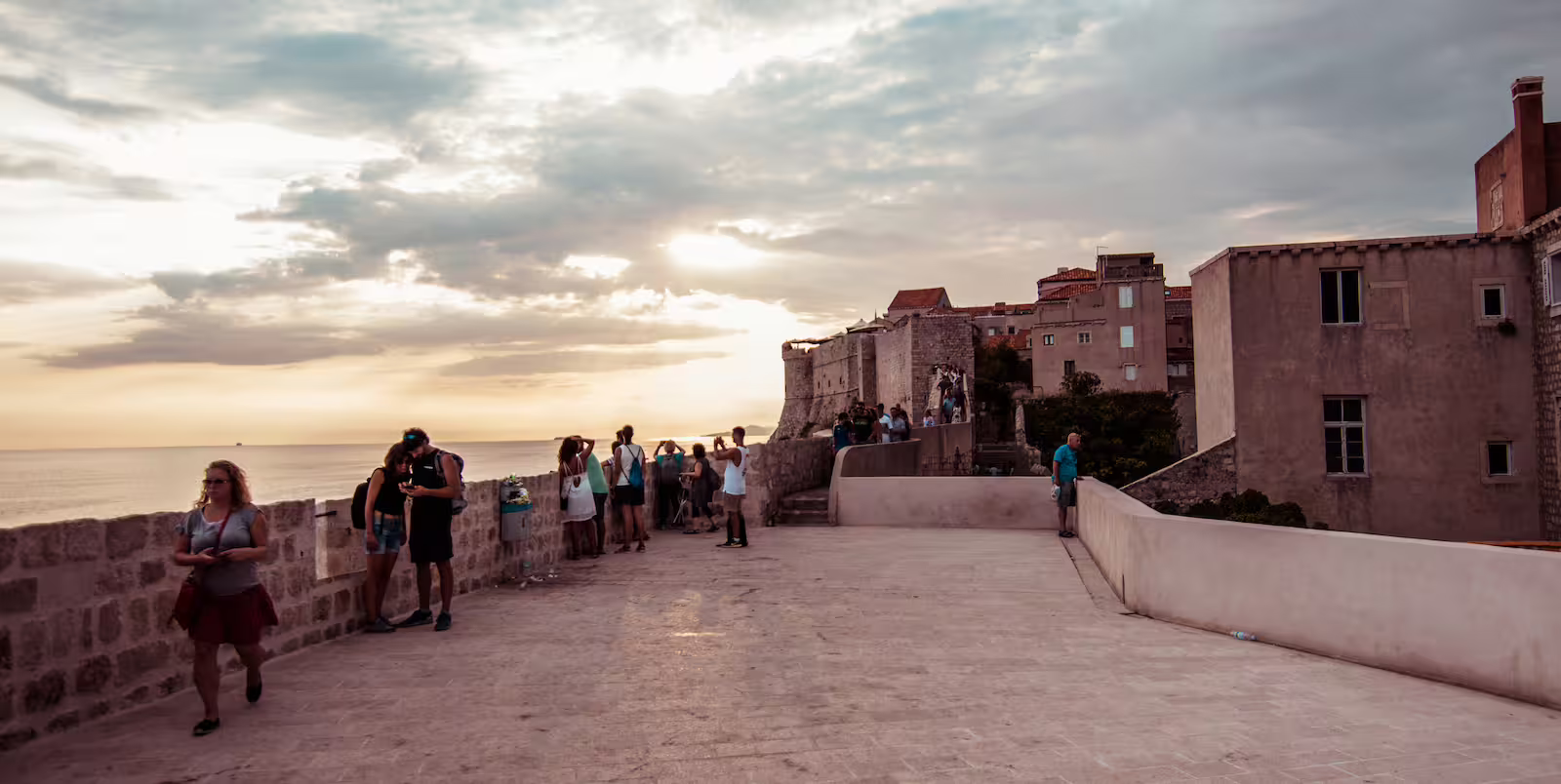 Sunset view from Dubrovnik City Walls on a private Old Town tour, with travelers watching the Adriatic Sea