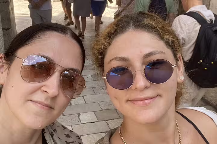Two women wearing sunglasses taking a selfie on a cobblestone street in Dubrovnik