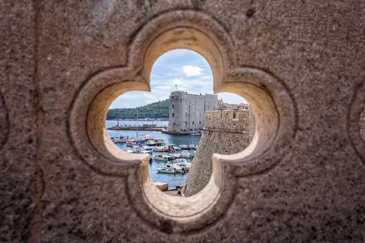 View of Dubrovnik harbor and fortress through a stone window, highlight on the King's Landing walking tour