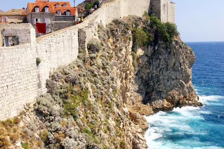 Dubrovnik medieval city walls above rocky cliffs and Adriatic waves on Ancient City Walls & Wars walking tour