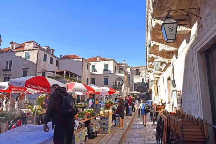 Morning market stalls and umbrellas near Dubrovnik Old Town, ideal stop on early bird walking group tour
