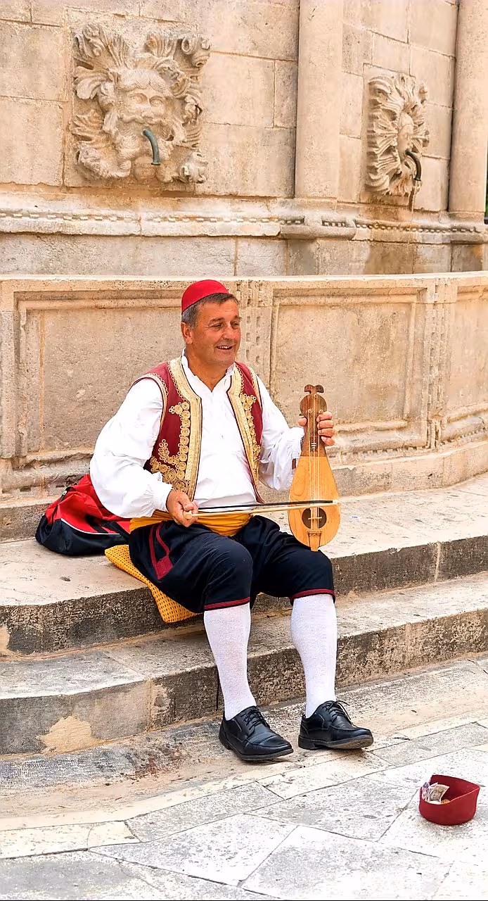 Traditional musician in Dubrovnik Old Town by stone fountain, cultural stop on Dubrovnik history city tour