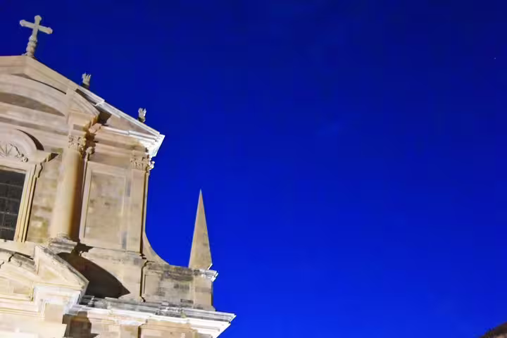 Illuminated Dubrovnik church facade against deep blue night sky, highlight on a Dubrovnik by night walking group tour