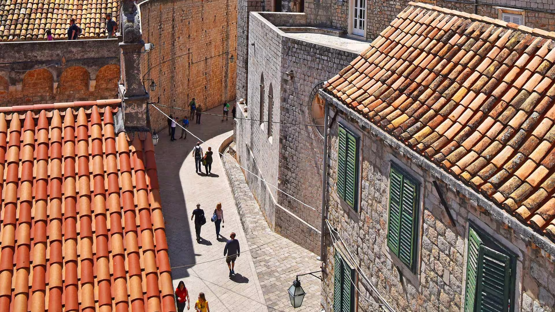 Dubrovnik Old Town street with red rooftops and stone houses, walking route on Game of Thrones history tour